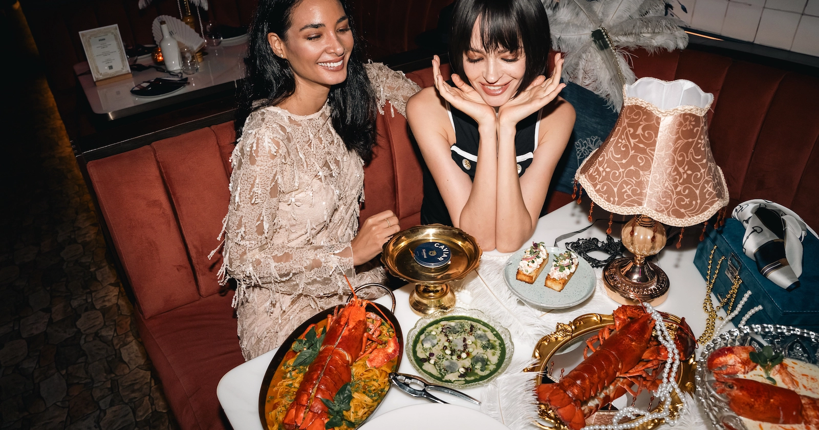 2 pretty models are eating lobster and drinking champagne at Pastel, a mediterranean restaurant in Bangkok