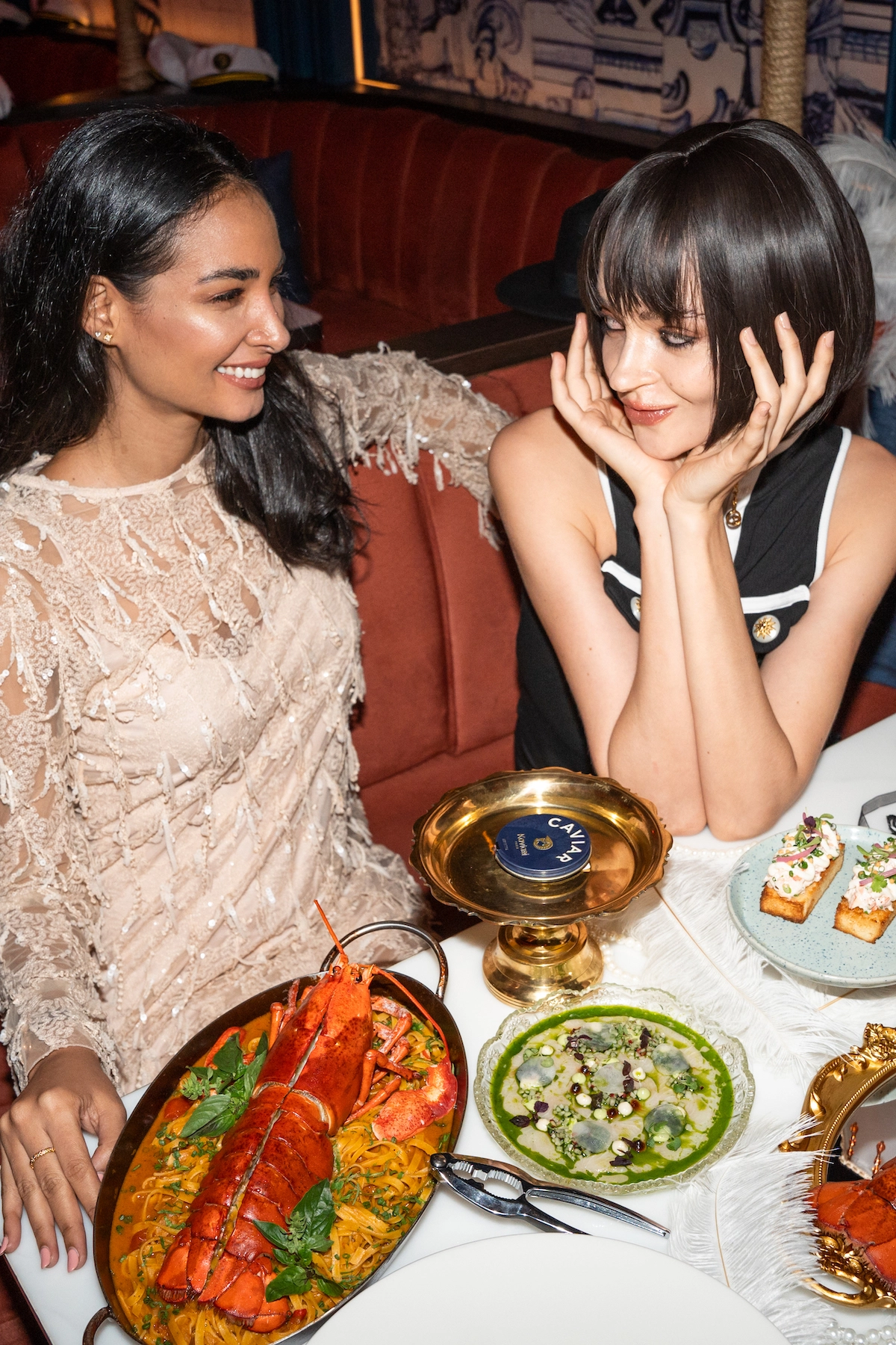 Beautiful female models smiling and eating caviar and lobster at Pastel rooftop bar in Bangkok